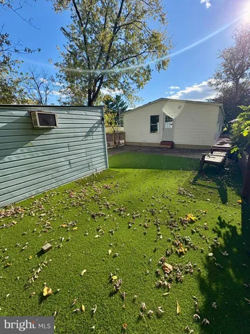 a backyard of a house with plants and large tree