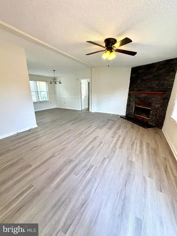 a view of a livingroom with wooden floor a ceiling fan and window