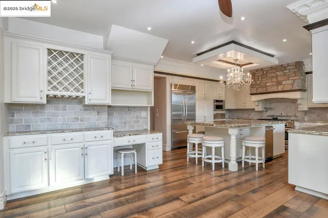 a kitchen with stainless steel appliances a dining table chairs sink and cabinets