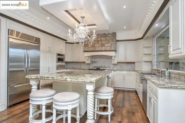 a kitchen with a stove a sink a kitchen island and chairs in it
