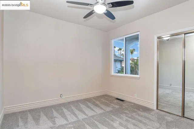 an empty room with closet and a chandelier fan