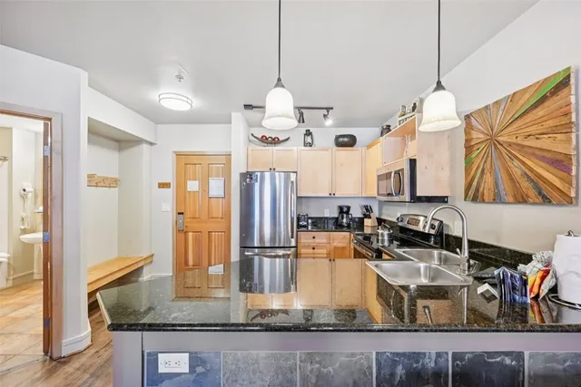 a kitchen with kitchen island granite countertop a sink a counter top space cabinets and stainless steel appliances