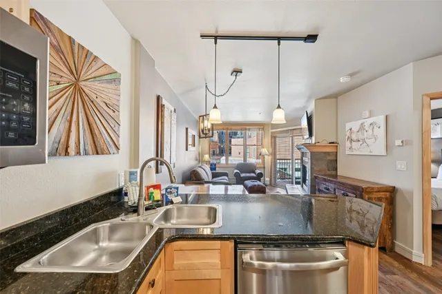 a kitchen with stainless steel appliances granite countertop a sink a microwave cabinets and a dining table with wooden floor