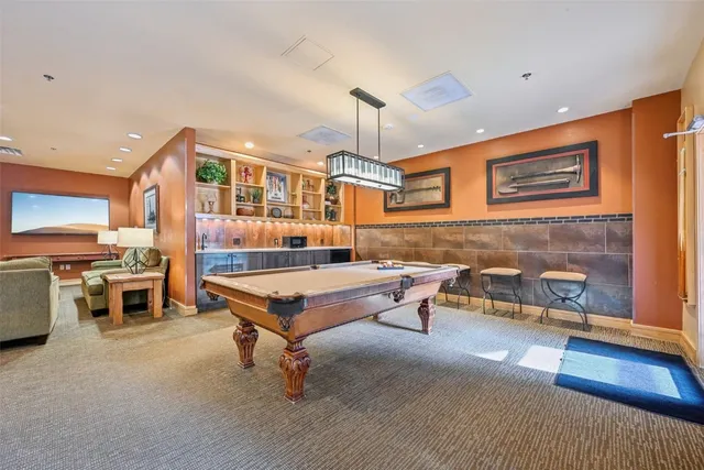 a living room with furniture pool table and chairs