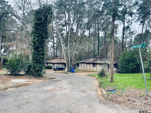 a front view of a house with a yard and large trees