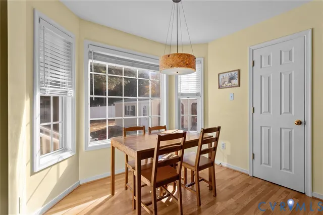 a dining room with wooden floor a chandelier a wooden table and chairs