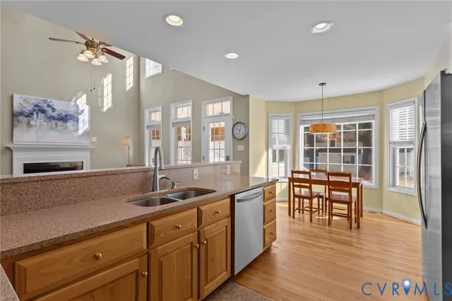 a large kitchen with stainless steel appliances a large window and a wooden floor