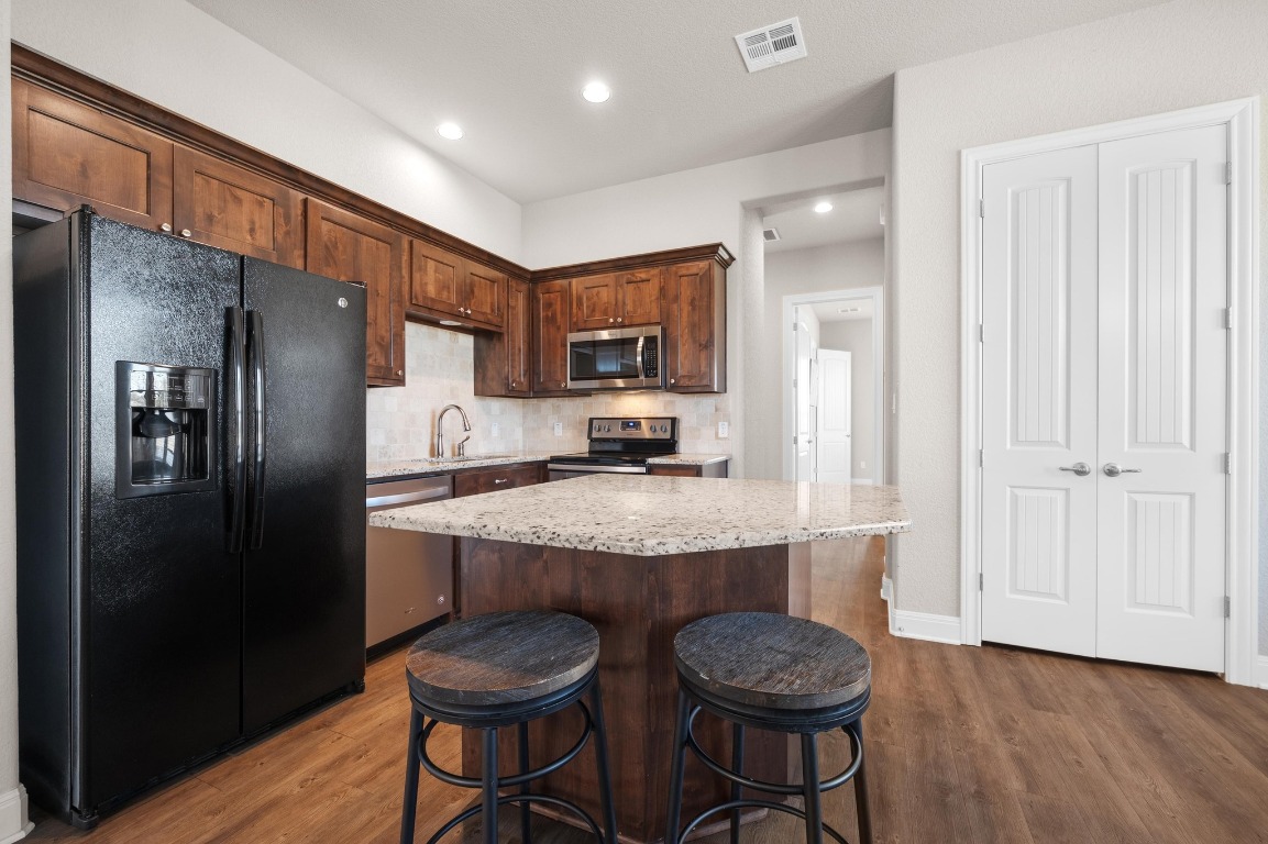 201 Young Ranch Road Georgetown, TX 78633 - Photo 29 of 40 a kitchen with granite countertop a refrigerator and a stove top oven