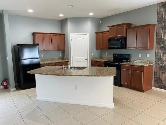 a kitchen with stainless steel appliances granite countertop a stove a sink a microwave a refrigerator a counter top space and cabinets