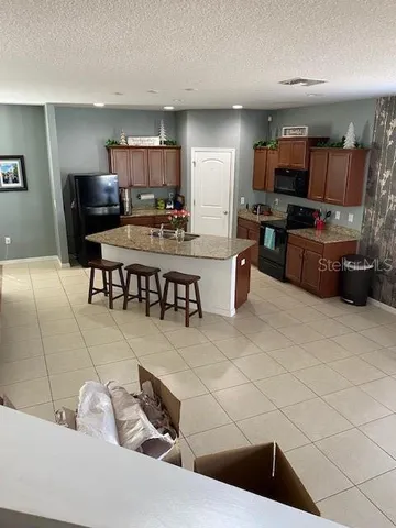 a kitchen with stainless steel appliances kitchen island granite countertop a sink and a refrigerator