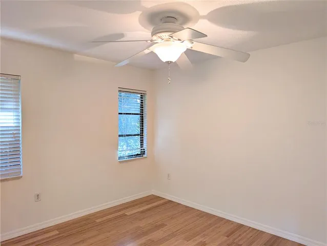 an empty room with wooden floor fan and window