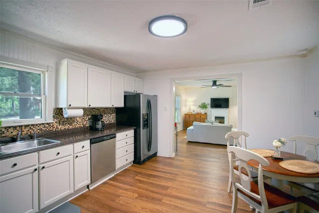 a kitchen with stainless steel appliances granite countertop a refrigerator a stove a sink dishwasher and white cabinets with wooden floor