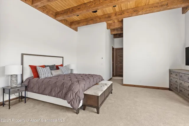 a spacious bedroom with a bed and a lamp on the dresser