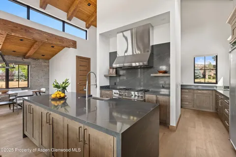 a kitchen with stainless steel appliances granite countertop a sink a stove and a wooden floors