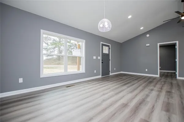 a view of empty room with wooden floor and kitchen view