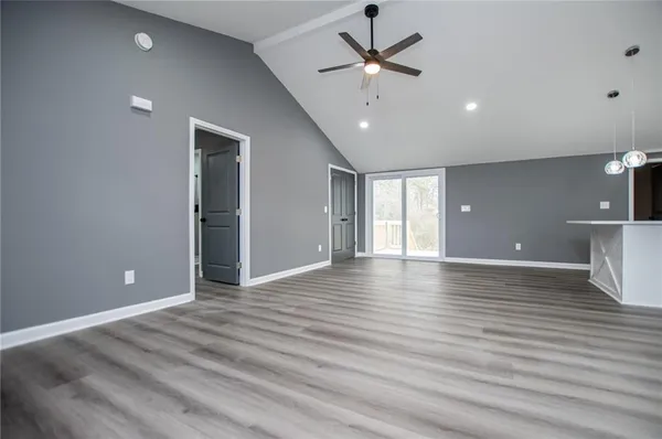 an empty room with wooden floor and ceiling fan