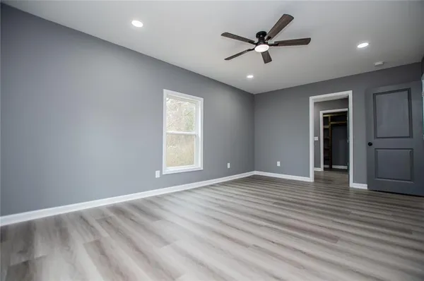 an empty room with wooden floor ceiling fan and windows