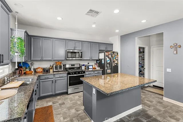 a kitchen with kitchen island granite countertop a sink a counter top space appliances and cabinets
