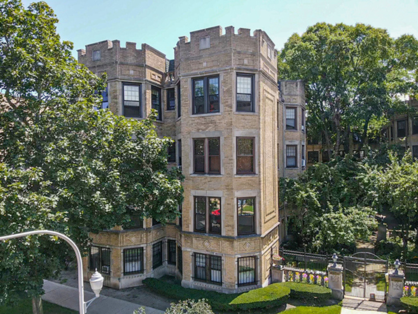 a front view of a residential apartment building with a yard and large trees