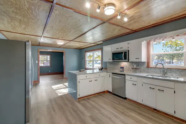 a living room with stainless steel appliances granite countertop a sink and a wooden floor