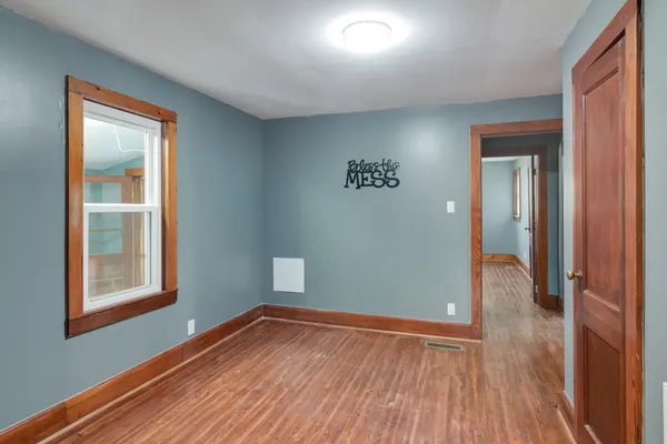 an empty room with wooden floor closet and windows