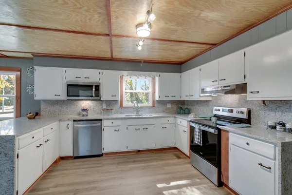 a kitchen with stainless steel appliances granite countertop a sink a stove and cabinets