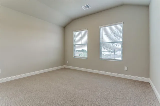 an empty room with chandelier fan and windows