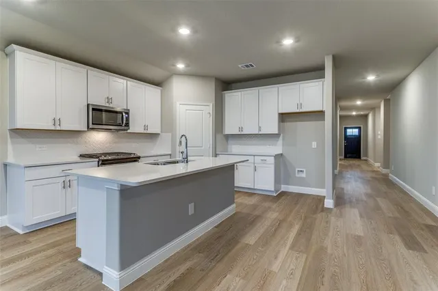 an empty room with wooden floor chandelier fan and windows