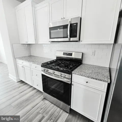 a kitchen with stainless steel appliances granite countertop white cabinets a microwave a sink and dishwasher