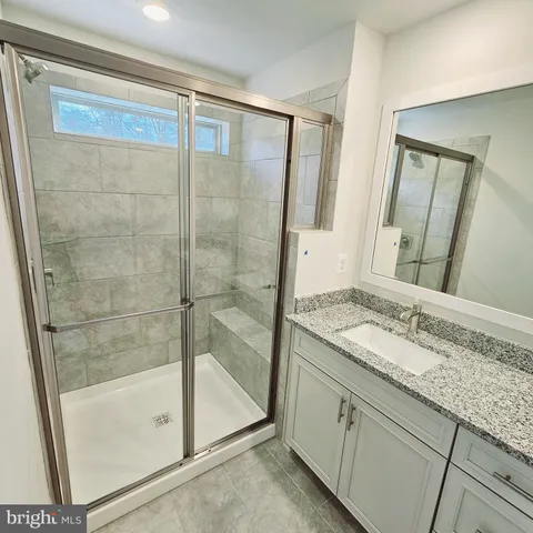 a bathroom with a granite countertop sink a mirror and a shower