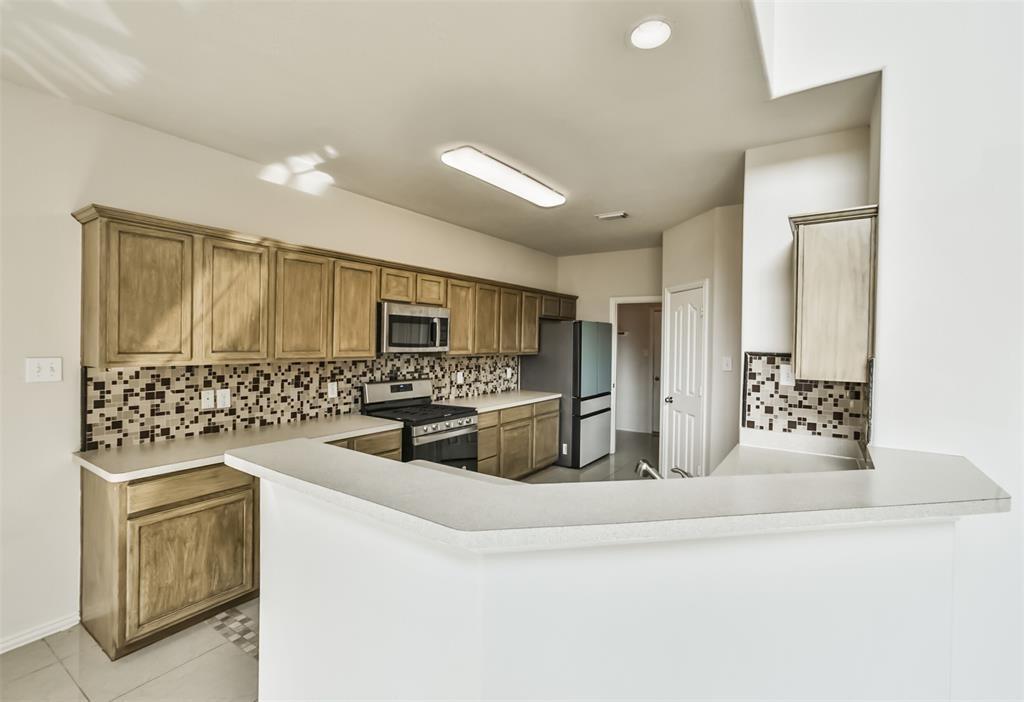 911 Merlin Roost Katy, TX 77494 - Photo 11 of 42 a kitchen with stainless steel appliances a sink a stove a microwave a counter top and cabinets
