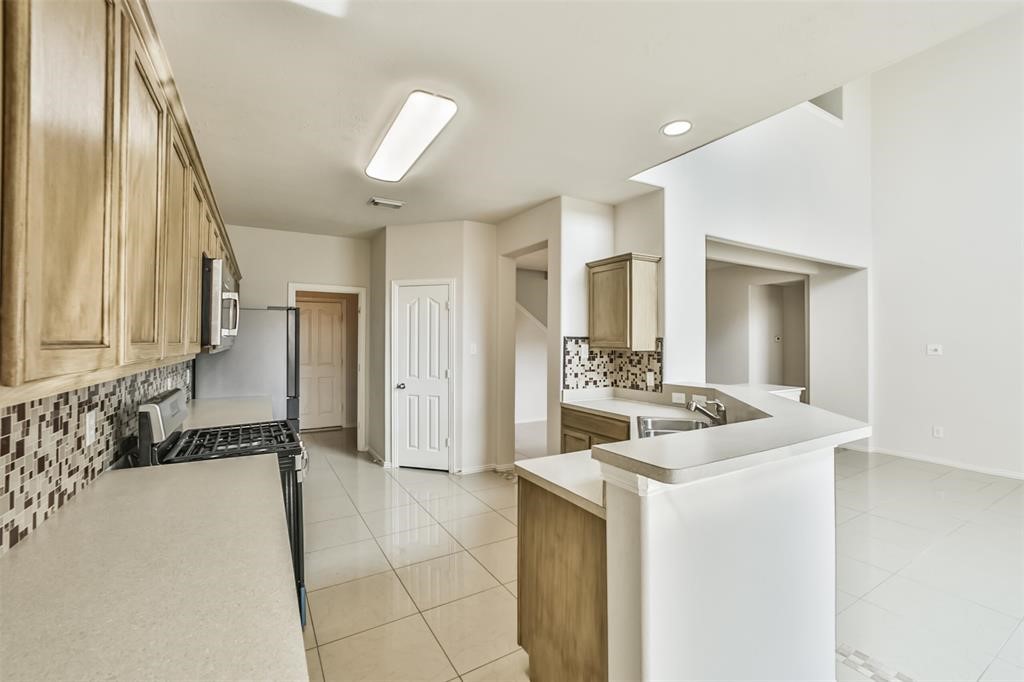 911 Merlin Roost Katy, TX 77494 - Photo 12 of 42 a view of a hallway with a sink and a refrigerator