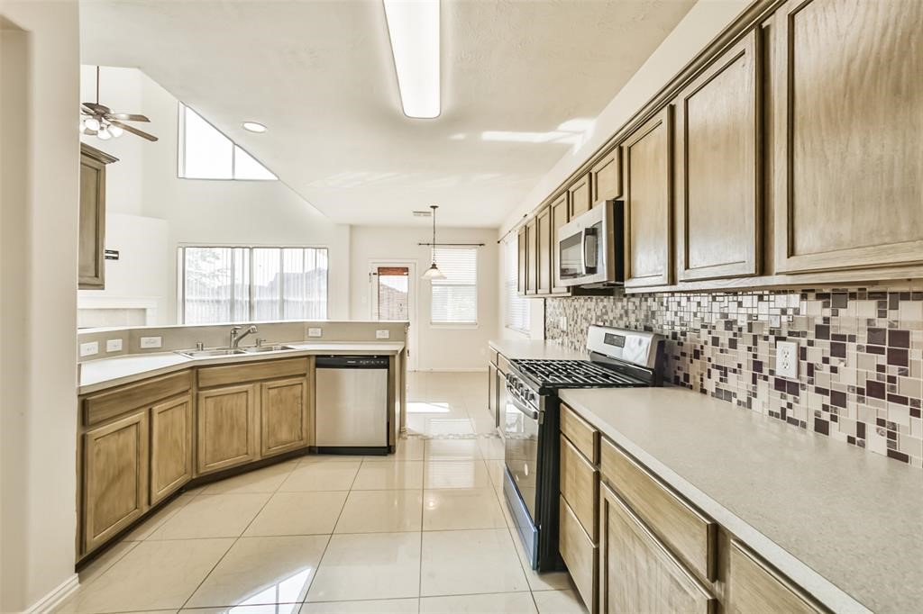 911 Merlin Roost Katy, TX 77494 - Photo 14 of 42 a kitchen with stainless steel appliances granite countertop a sink and cabinets