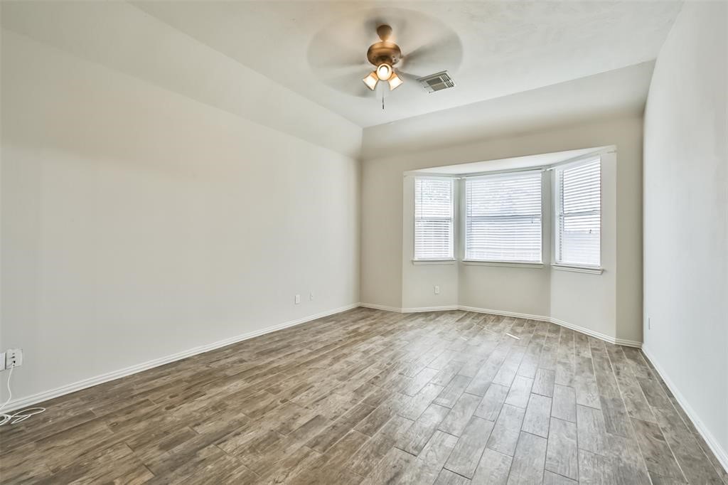 911 Merlin Roost Katy, TX 77494 - Photo 25 of 42 an empty room with wooden floor chandelier fan and windows