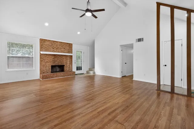 an empty room with wooden floor a fireplace and windows