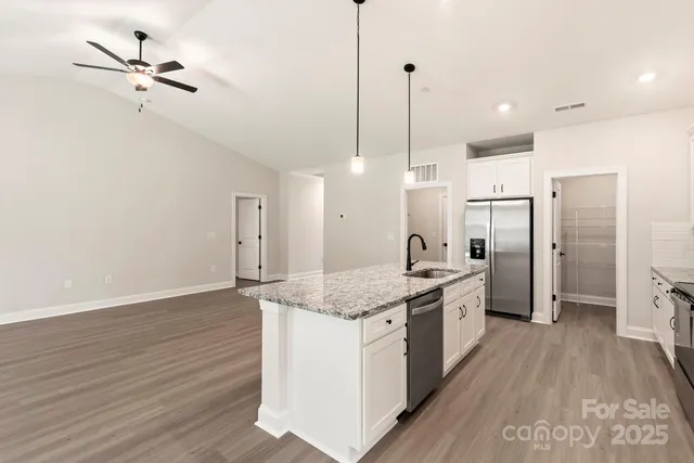 a kitchen with stainless steel appliances granite countertop a sink a refrigerator and a stove