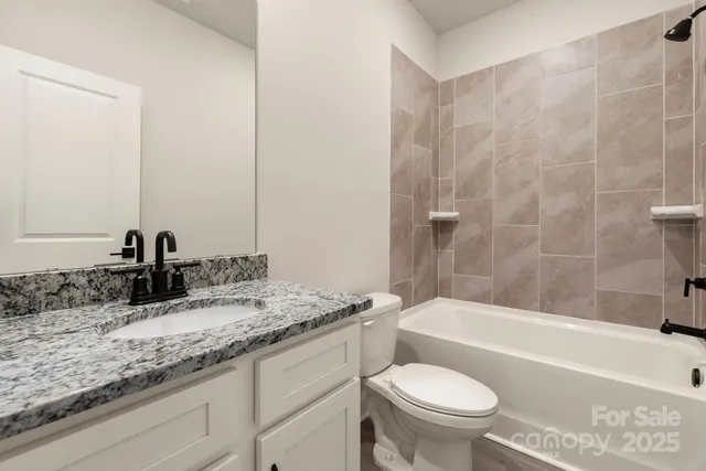 a bathroom with a granite countertop toilet a sink and a bathtub