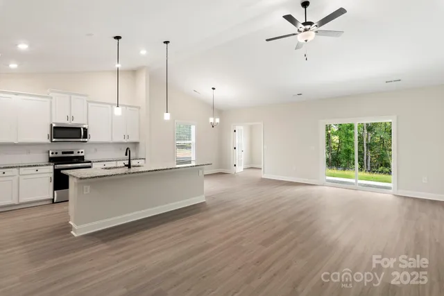 a view of a kitchen with stainless steel appliances a large window a sink and wooden floor