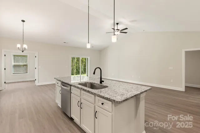 a kitchen with stainless steel appliances granite countertop a sink a center island and a wooden floor