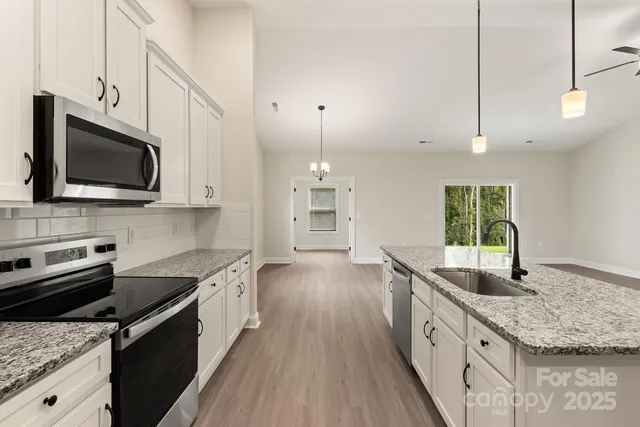 a kitchen with stainless steel appliances granite countertop a sink stove and microwave