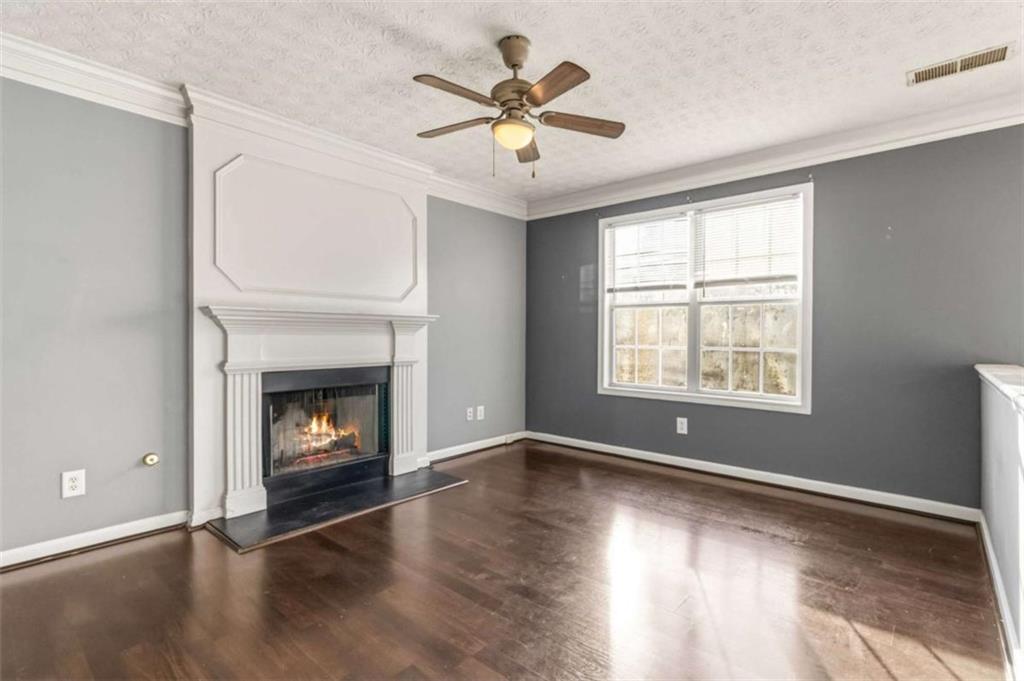 4170 Jewel Terrace Conley, GA 30288 - Photo 8 of 29 an empty room with windows a fireplace a ceiling fan and wooden floor