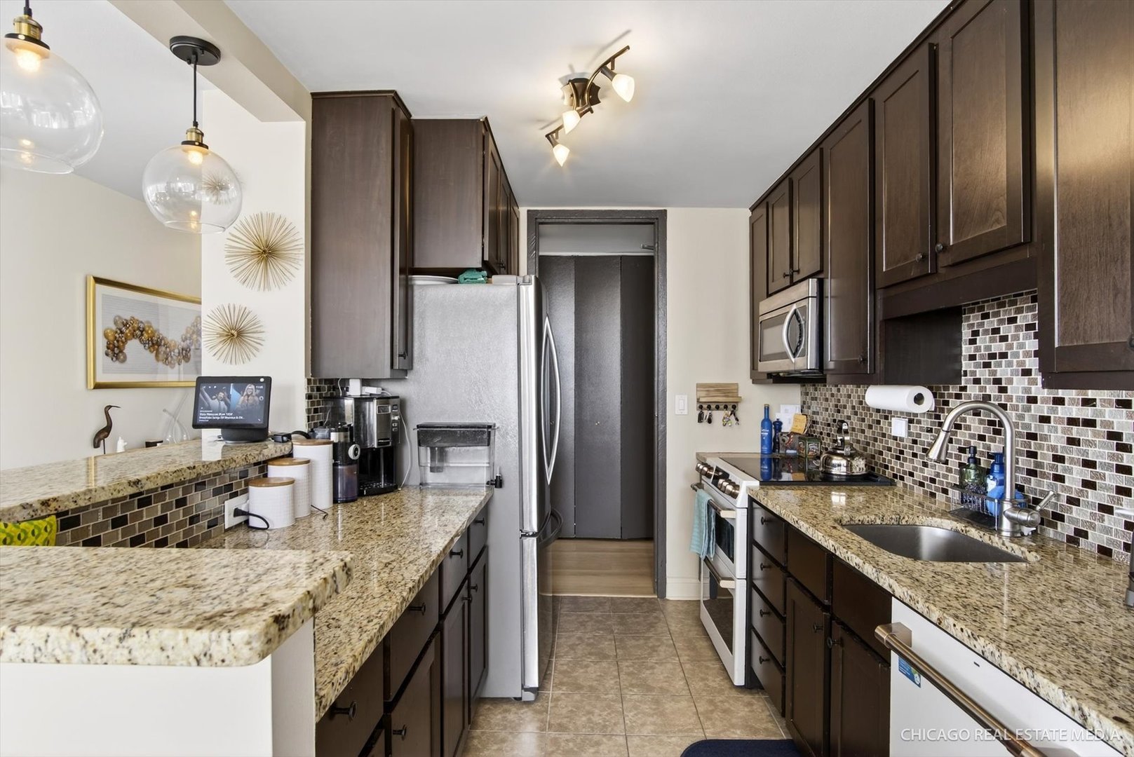 655 West Irving Park Road, Unit 1101 Chicago, IL 60613 - Photo 13 of 26 a kitchen with stainless steel appliances granite countertop a sink refrigerator and cabinets
