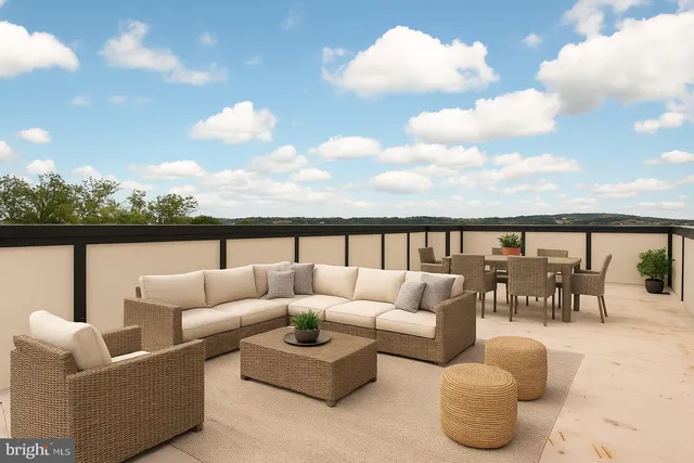 a roof deck with couches and sky view