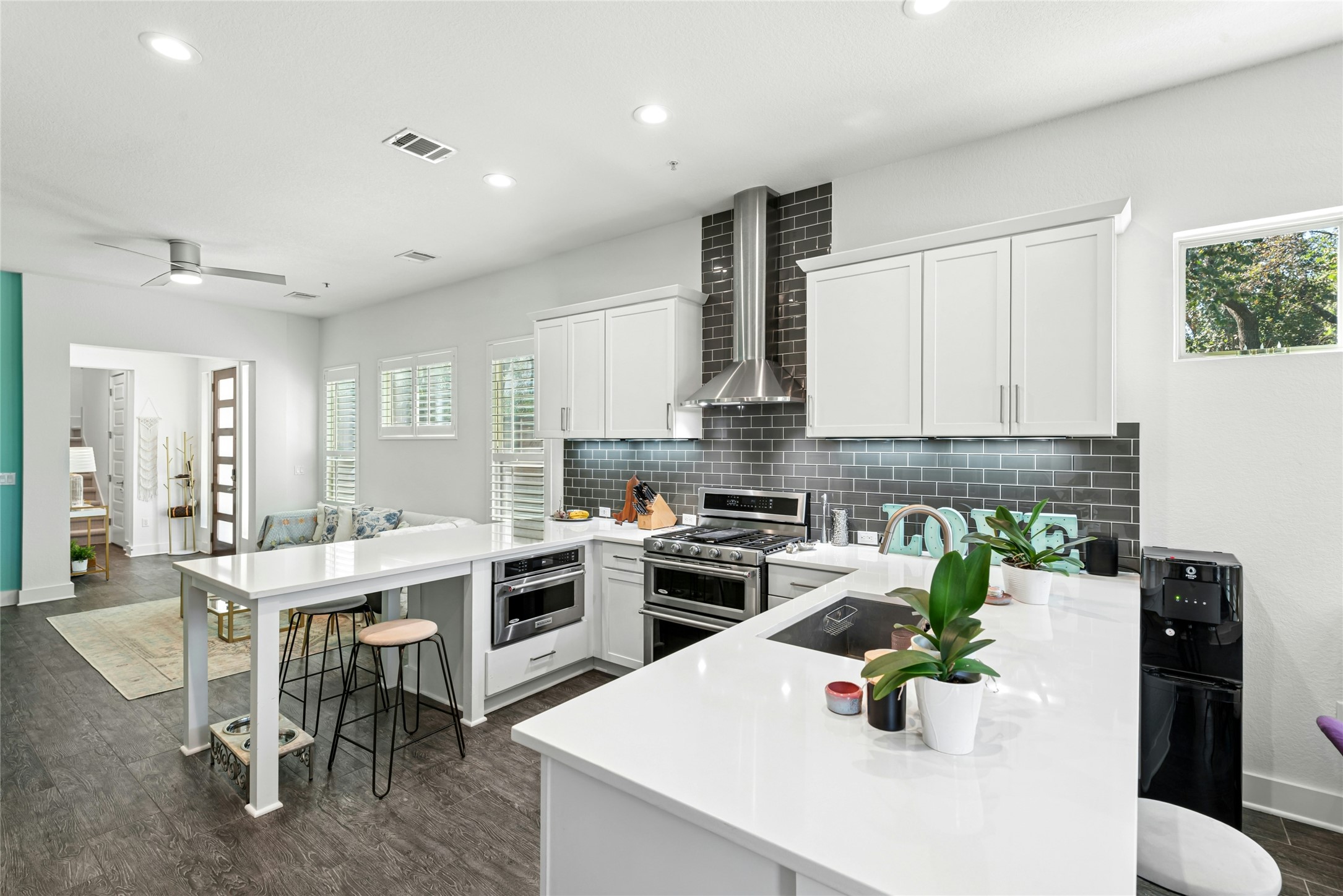 404 West Alpine Road, Unit 17 Austin, TX 78704 - Photo 12 of 35 Kitchen featuring a peninsula, a kitchen bar, stainless steel appliances, dark wood finished floors, and white cabinetry