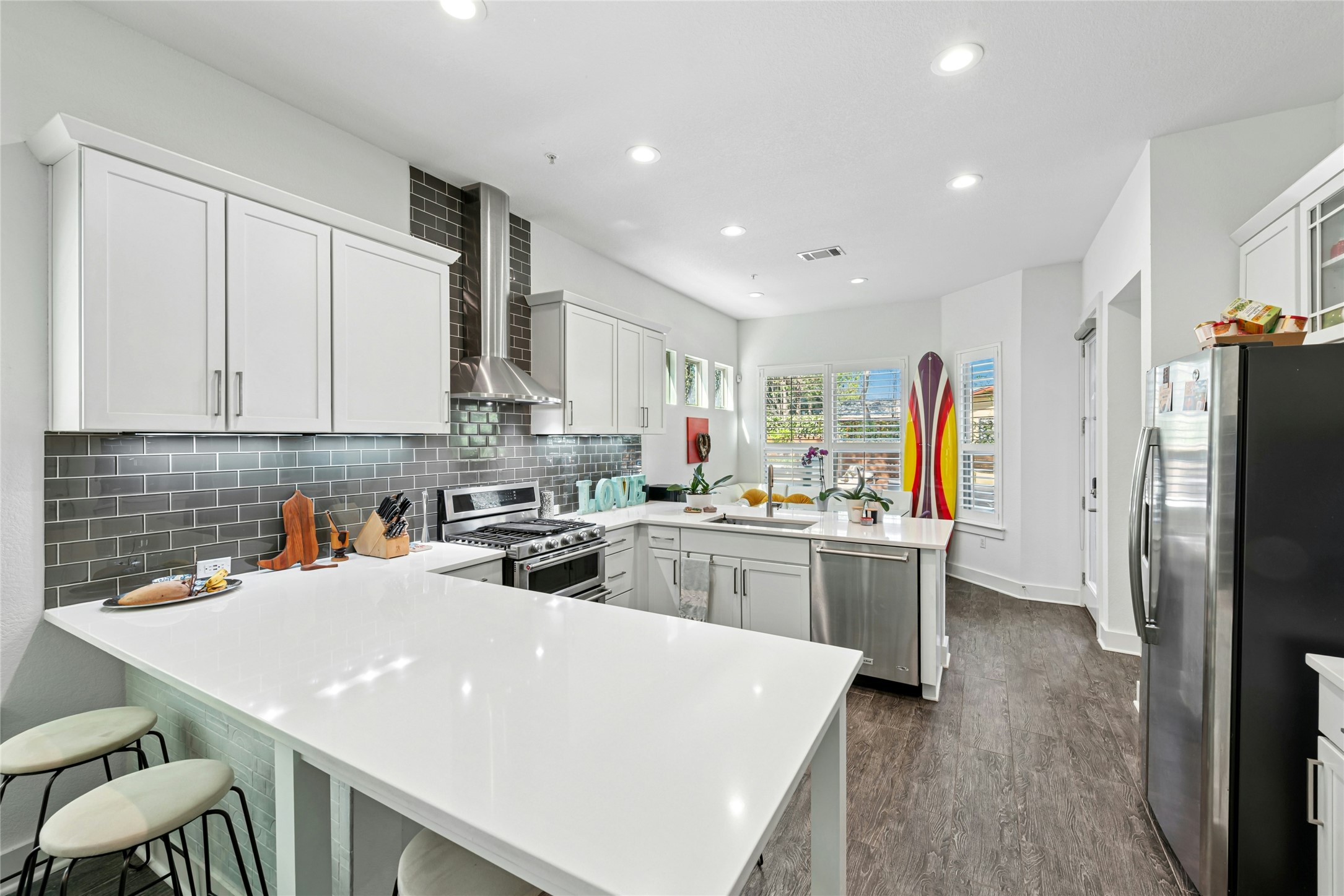 404 West Alpine Road, Unit 17 Austin, TX 78704 - Photo 13 of 35 Kitchen featuring a peninsula, stainless steel appliances, white cabinetry, a kitchen breakfast bar, and decorative backsplash