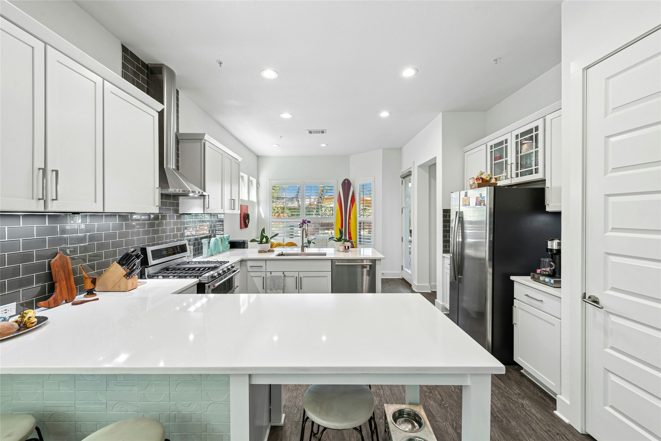 404 West Alpine Road, Unit 17 Austin, TX 78704 - Photo 15 of 35 Kitchen featuring a peninsula, glass insert cabinets, stainless steel appliances, decorative backsplash, and light stone countertops