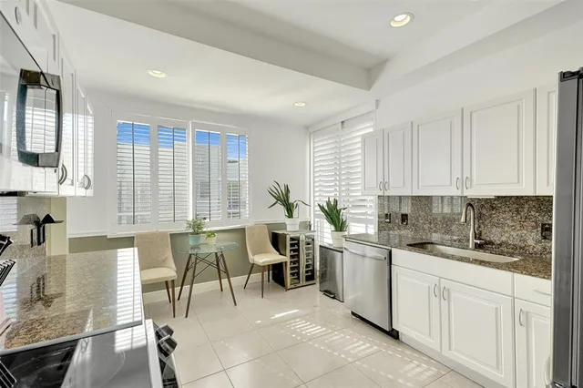 a kitchen with a sink white cabinets and glass table chairs
