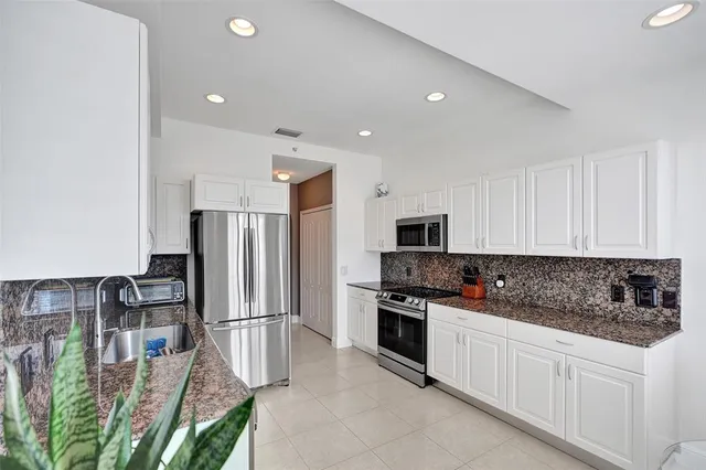 a kitchen with stainless steel appliances granite countertop a refrigerator sink and stove