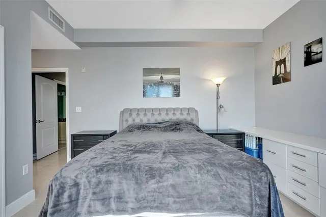 a bedroom with a bed and a lamp on dresser