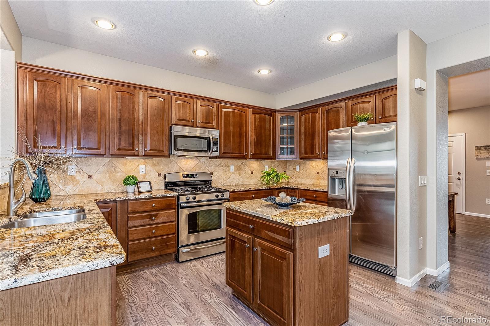 592 Brookhurst Avenue, Unit 26B Highlands Ranch, CO 80129 - Photo 12 of 19 a kitchen with stainless steel appliances granite countertop a stove top oven a sink and dishwasher a refrigerator with wooden floor